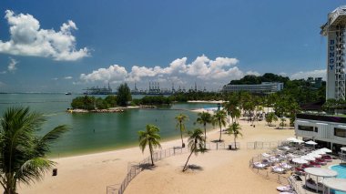 Sentosa Adası sahil şeridinin panoramik perspektifi dinlenme yerleri, palmiye ağaçları ve tropikal manzaralar.