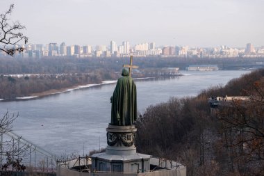 KYIV, UKRAINE - 07 Ocak 2023: Kyiv tepelerindeki Aziz Vladimir Anıtı. Yaya köprüsü ve Büyük Vladimir Anıtı ile Dnipro Nehri 'nin manzarası.