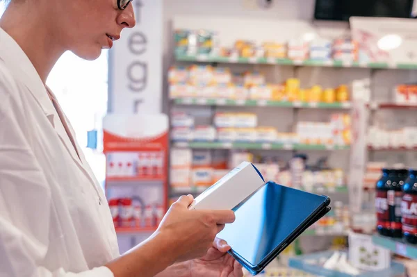 Woman pharmacist checks medicines on the tablet