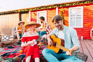 Bir grup arkadaş piknik yapıp gitarla oynuyorlar.