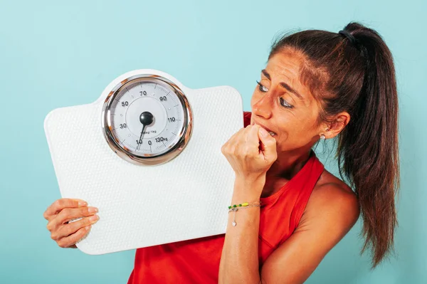 Scared woman is afraid of weight measurement with scale