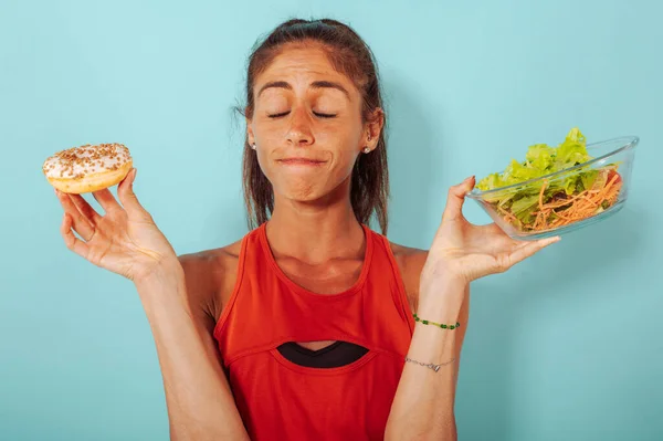 Woman is not sure to eat donuts instead of a salad