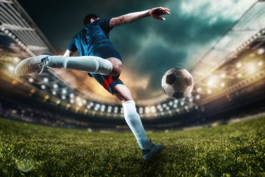Futbolcu stadyumda topa güçlü bir şekilde vuruyor.