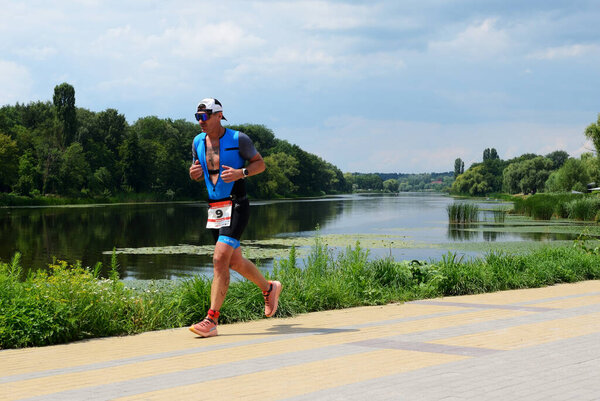 BILA TSERKVA, UKRAINE - JULY 23: The athlete compete in running component on embankment near Ros river during national triathlon competition of Ukraine on July 23, 2023 in Bila Tserkva, Ukraine.