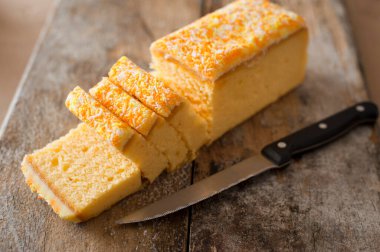 Mutfak bıçağıyla ahşap bir tahtada servis edilmek üzere dilimlenmiş taze pişmiş somun kek.