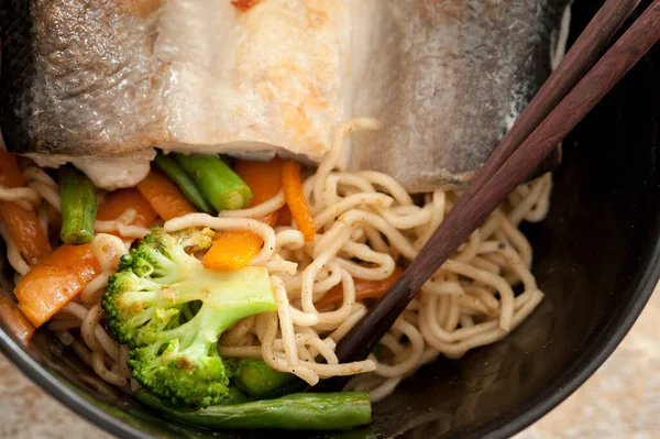 麺と新鮮な野菜を盛り付けたミルクフィッシュを椀に盛り 箸で頭上から間近で見ることができる ストック画像