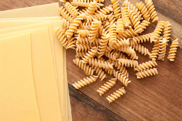 将意大利生面食分类 放在木制桌子上 上面有螺旋形的茴香面和床单 可用于头顶上的意大利面 图库照片