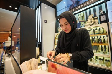 SINGAPORE - CIRCA JANUARY, 2020: Kadın Nge Ann City alışveriş merkezindeki Sephora mağazasında malları paketliyor.