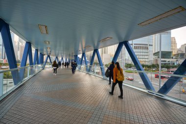 HONG KONG - CIRCA, 2019: İnsanlar Central Ferry Piers ile IFC AVM 'yi birbirine bağlayan köprü boyunca yürür.