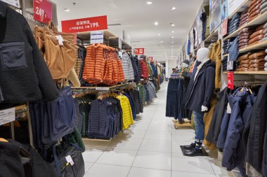 SHENZHEN, ÇİN - CIRCA NOVEMBER, 2019: Shenzhen 'deki Uniqlo mağazasında giysi sergileniyor. Uniqlo bir Japon günlük giyim tasarımcısı, üretici ve perakendecisi..