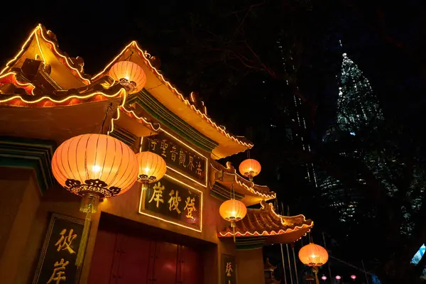 stock image KUALA LUMPUR, MALAYSIA -  MAY 29, 2023: street level view of entrance gate of Po Ling Temple with Petronas Towers in the background in the night.