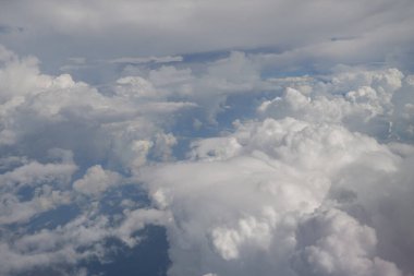 Uçaktan bulutların üzerinden görünen hava görüntüsü.