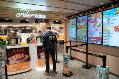 HONG KONG, ÇİN - 04 Aralık 2023: Hong Kong 'daki Cafe de Coral' da yemek sipariş eden bir adam.