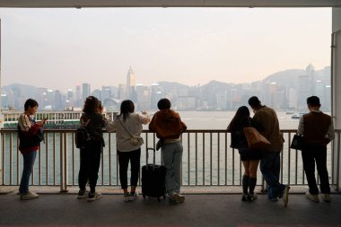 HONG KONG, CHINA - DECEMBER 05, 2023: people stand at Harbour City with Hong Kong Island in the background.  clipart