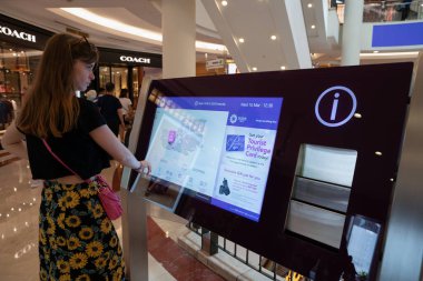 KUALA LUMPUR, MALAYSIA - 15 Mart 2023: Bir kadın Kuala Lumpur 'daki Suria KLCC alışveriş merkezinde etkileşimli bilgi kiosku kullanır.