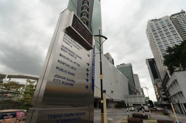 JOHOR BAHRU, MALAYSIA - NOVEMBER 23, 2023: a directional signboard pointing to various landmarks, including a bank, temples, and other locations in Johor Bahru, with a temperature display on top. clipart