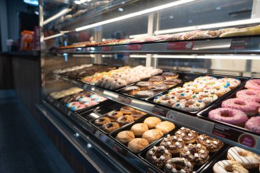 KUALA LUMPUR, MALAYSIA - 28 Kasım 2023: Donutlar Ampang Park MRT istasyonundaki Dunkin 'Donuts konteynır konsepti içinde cam bir vitrinde sergilendi.