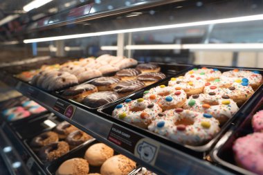 KUALA LUMPUR, MALAYSIA - 28 Kasım 2023: Donutlar Ampang Park MRT istasyonundaki Dunkin 'Donuts konteynır konsepti içinde cam bir vitrinde sergilendi.