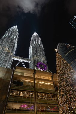 KUALA LUMPUR, MALAYSIA - DECEMBER 02, 2023: a replica of a Christmas tree at the Esplanade with the Suria KLCC and the Petronas Towers in the background. clipart