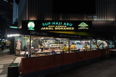 KUALA LUMPUR, MALAYSIA - DECEMBER 02, 2023: street-level view of Sup Haji Abu and Nasi Kandar Jamal Mohamed (Bawah Pokok), a popular eatery near KLCC at night. clipart