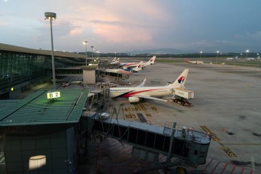 KUALA LUMPUR, MALAYSIA - DECEMBER 03, 2023: several Malaysia Airlines Boeing 737s on the tarmac, with boarding bridges at KL International Airport. clipart