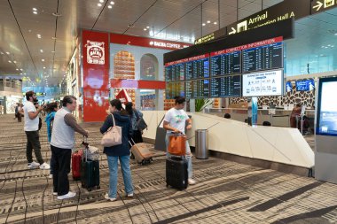 SINGAPORE - 25 AĞUSTOS 2024: Changi Havalimanı yolcuları Nakil Odası A 'nın yanında, Uçuş Bilgileri Ekranındaki uçuş detaylarını kontrol ediyorlar (FIDS).