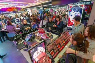 Hong Kong, China - February 02, 2019: customers browsing Shu Uemura make up products in a retail area at Harbour City, Hong Kong. clipart