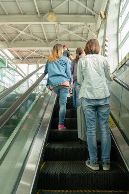 Busan, Güney Kore - 24 Mayıs 2017: Gimhae Uluslararası Havaalanı metro istasyonunda yürüyen merdivene binen yolcular.