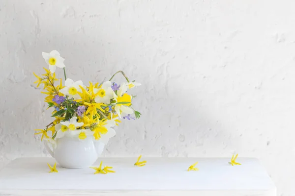 白色和黄色的春花在木制桌子上的花瓶里 背景是白色的 — 图库照片