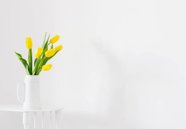 Beyaz arkaplanda vazoda sarı laleler