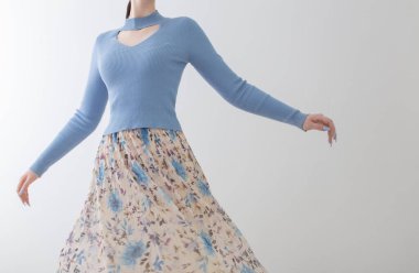 Mavi bluzlu genç kız ve beyaz arka planda pileli etek.