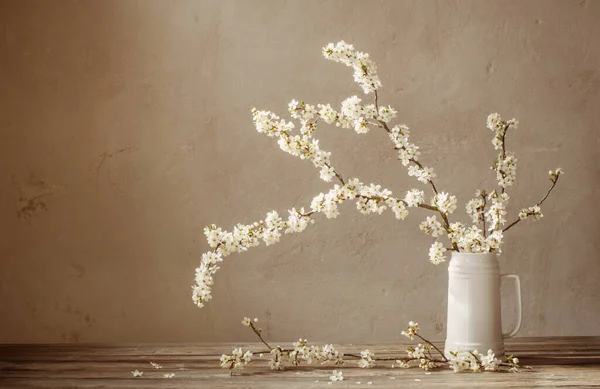 古い木製のテーブルの上に白いジャグの桜の花 — ストック写真