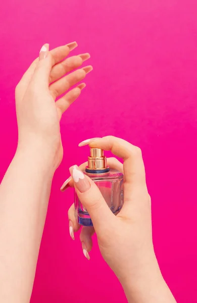 Vrouwelijke Handen Met Parfum Fles Roze Achtergrond — Stockfoto