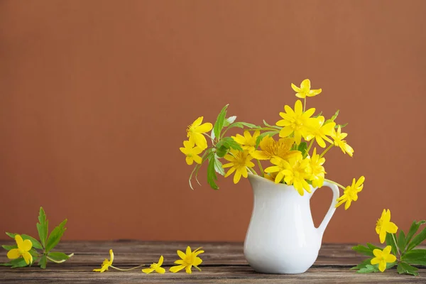 茶色の背景に黄色い春の花をジャグで静物 — ストック写真
