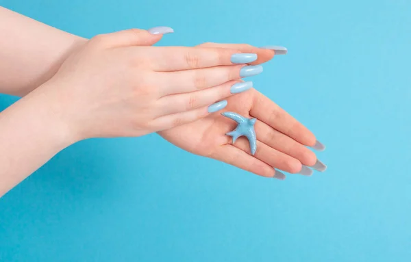 Weibliche Hand Mit Maniküre Und Keramikvogel Auf Blauem Hintergrund — Stockfoto