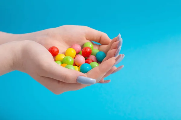 Weibliche Hand Mit Bonbons Auf Blauem Hintergrund — Stockfoto