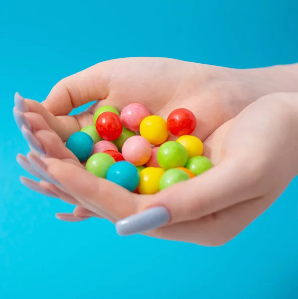 Weibliche Hand Mit Bonbons Auf Blauem Hintergrund — Stockfoto