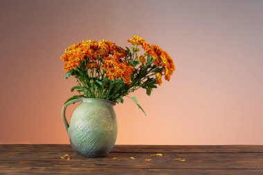 Ahşap arka planda vazoda portakal kasımpatıları