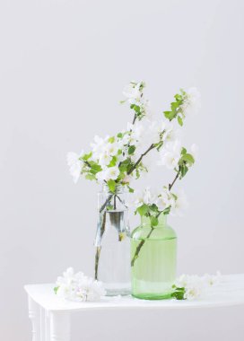 Beyaz iç kısımda cam vazoda elma çiçekleri.