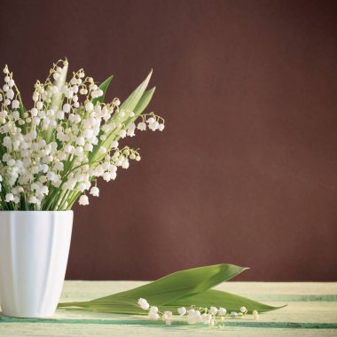 Vadideki zambak vazoda, kahverengi arka plandaki ahşap masada.