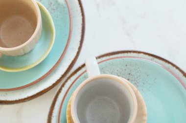 Beyaz mermer masada iki seramik bardak ve tabak.