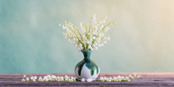 在绿色背景的木制桌子上的花瓶里的百合花 — 图库照片