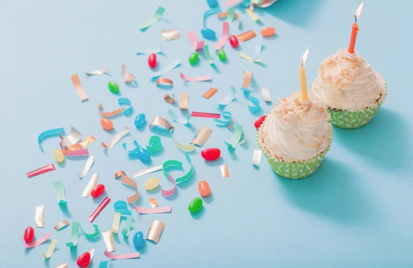 Geburtstagsmütze Mit Konfetti Und Cupcake Mit Brennender Kerze Auf Blauem — Stockfoto