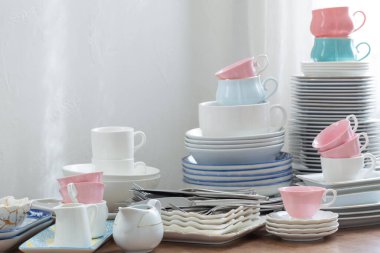 Pembe, beyaz abd mavi çatal bıçak seti ahşap bir masada beyaz bir duvara karşı