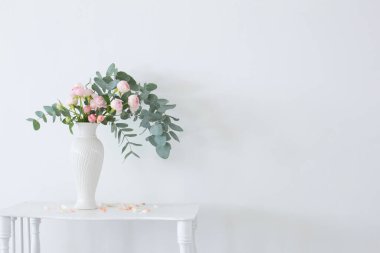 Beyaz eski ahşap rafta seramik beyaz vazoda pembe güller buketi