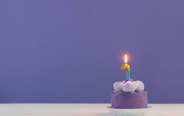 mor arkaplanda yanan mumlarla birlikte mor doğum günü pastası