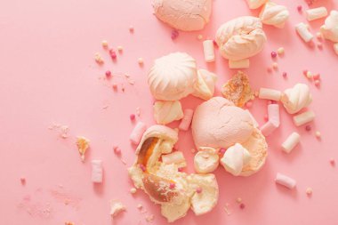 Düşmüş ve kırılmış şekerler pembe arka planda