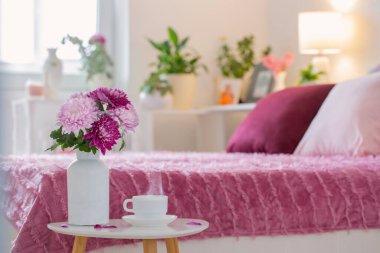 Beyaz bardakta sıcak içecek arka planda pembe ve beyaz yatak odasında.