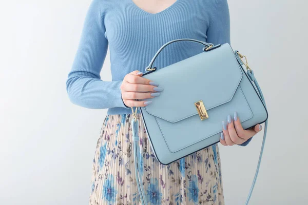 stock image young girl in blue blouse  and pleated skirt with blue handbag on white background