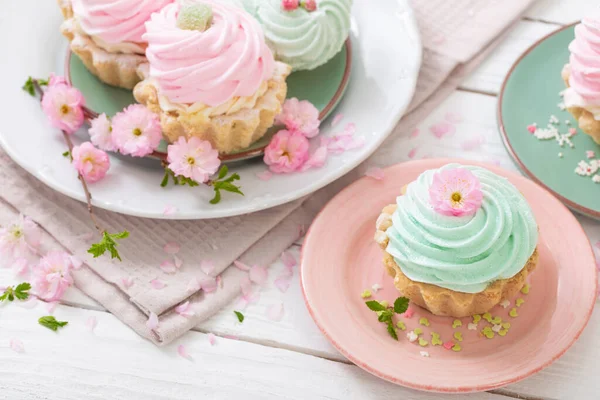 ピンクと緑のカップケーキ白い木の背景に春の花 — ストック写真